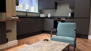 A modern kitchen with dark cabinetry, a skylight, and a dining area with a table and chair. - Terrific 2-bedroom apartment in central London perfect for your stay (London)