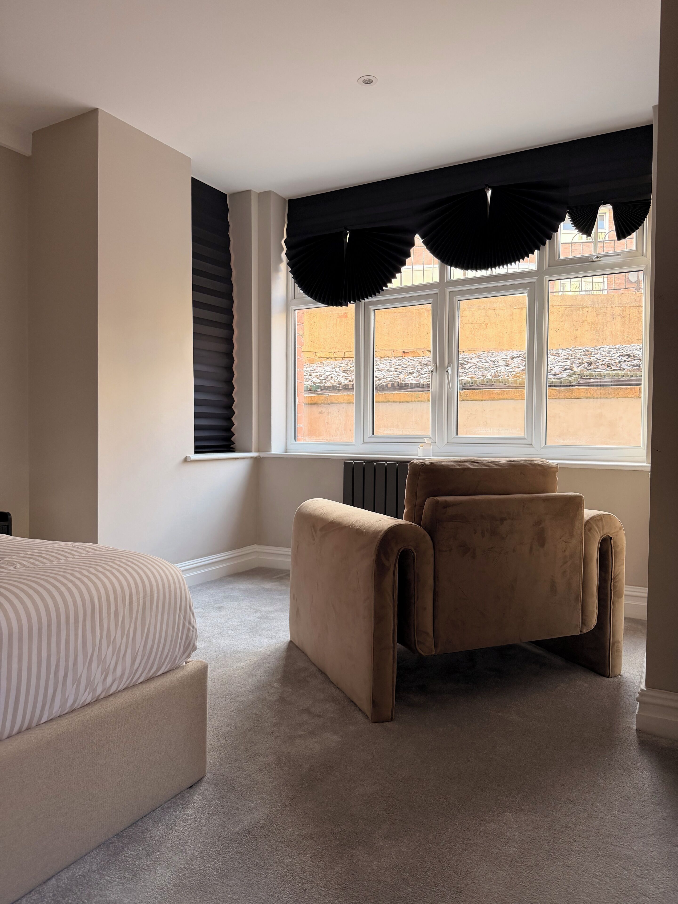 Une chambre à coucher avec un lit, une chaise, un radiateur et une fenêtre avec des stores.