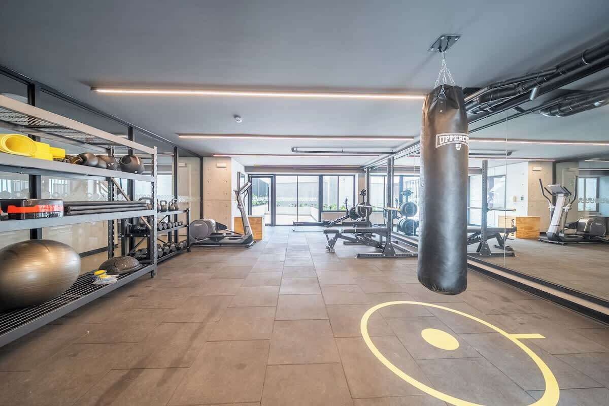Une salle de sport équipée de matériel d’exercice, d’un sac de frappe et d’un mur recouvert de miroirs.