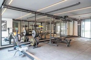 A modern gym with weightlifting equipment, mirrors, and a clean, spacious layout. - Steps from Larcomar | 3BR · A/C · Parking (Miraflores)