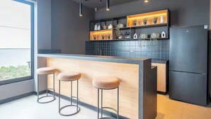 A modern kitchen with a bar area, pendant lighting, and a view through a large window. - Steps from Larcomar | 3BR · A/C · Parking (Miraflores)