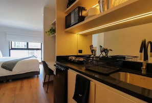 Ein kleines Hotelzimmer mit Bett, einer Küchenzeile und Blick auf die Stadt.