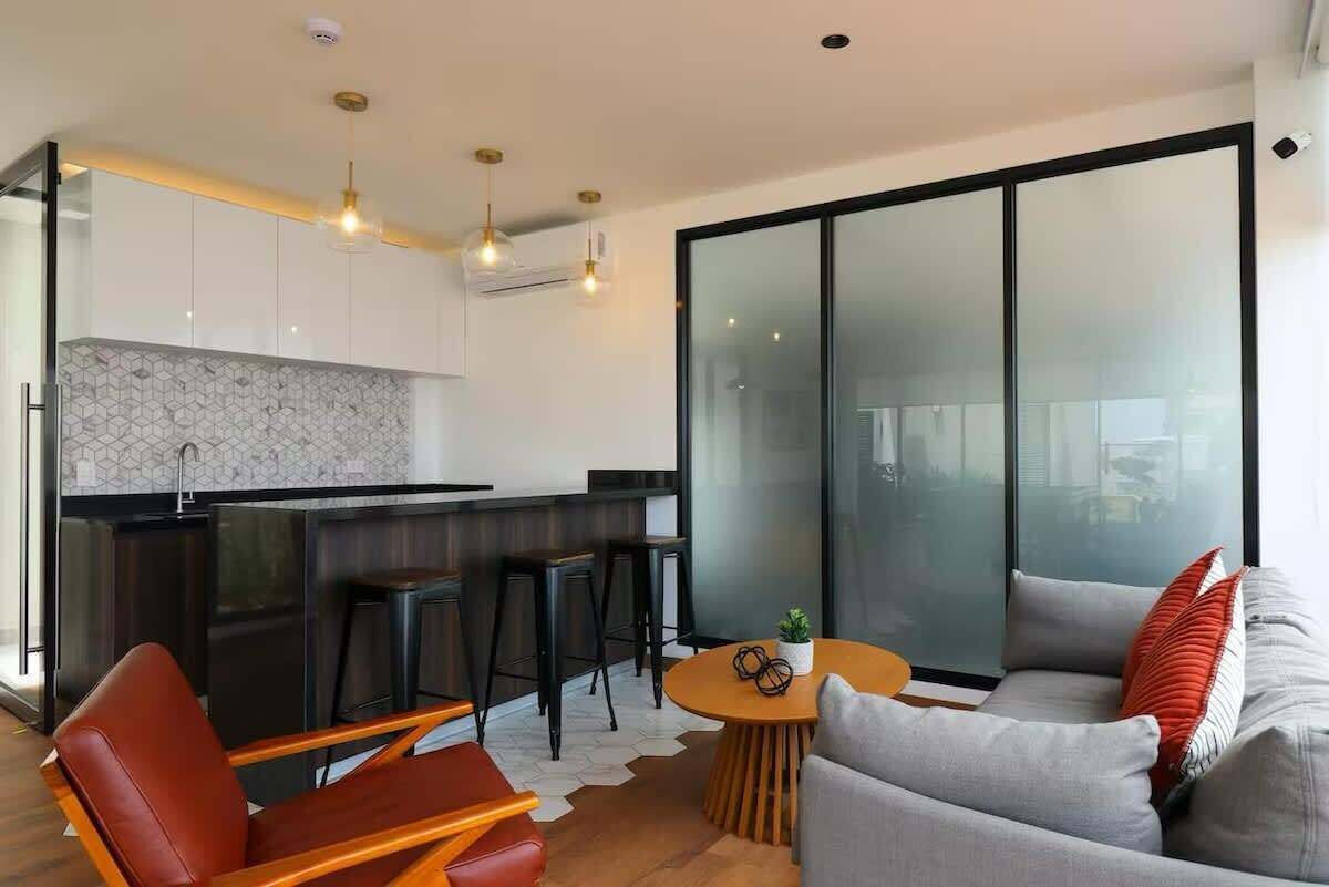 Eine moderne Küche mit Bar, einer Sitzecke mit Sofa und Stühlen sowie einer großen Schiebeglasdoor.