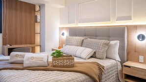 Hotellihuone, jossa on suuri sänky, puupaneloitu seinä ja yöpöytä, jossa on lamppu.