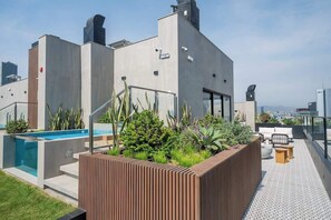 A rooftop terrace with a swimming pool, outdoor seating, and a view of the cityscape. - Pool · Gym · A/C | San Isidro's Financial District (San Isidro)