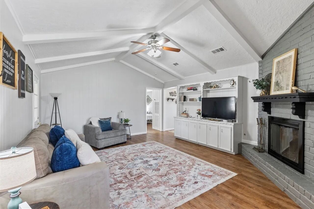 A spacious living room with a high ceiling, a fireplace, a television, and a cozy seating area.