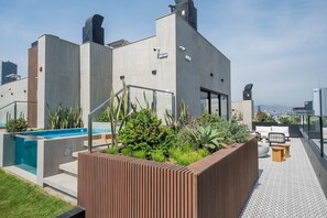 A rooftop terrace with a swimming pool, outdoor seating, and a view of the city skyline. - San Isidro Business Hub | Pool · Gym · Parking (San Isidro)
