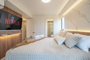Un dormitorio moderno con una cama grande, un televisor de pantalla plana montado en la pared y un diseño minimalista.