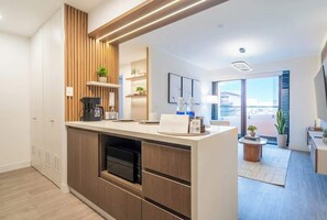 A modern kitchen with built-in appliances, a wooden accent wall, and a view to the outside. - San Isidro Business Hub | Pool · Gym · Parking (San Isidro)
