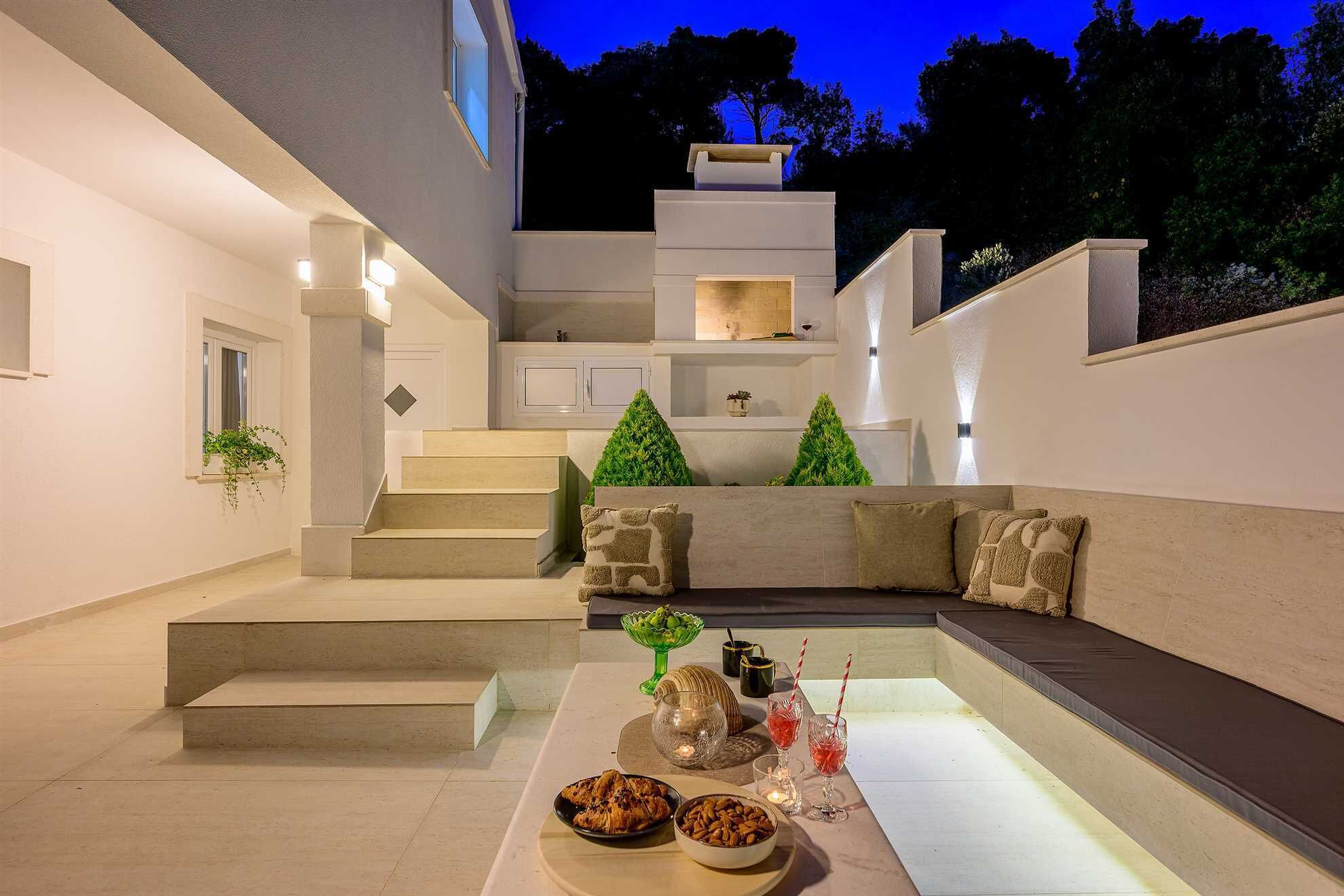 A modern outdoor living area with a built-in seating area, a staircase, and a dining setup.