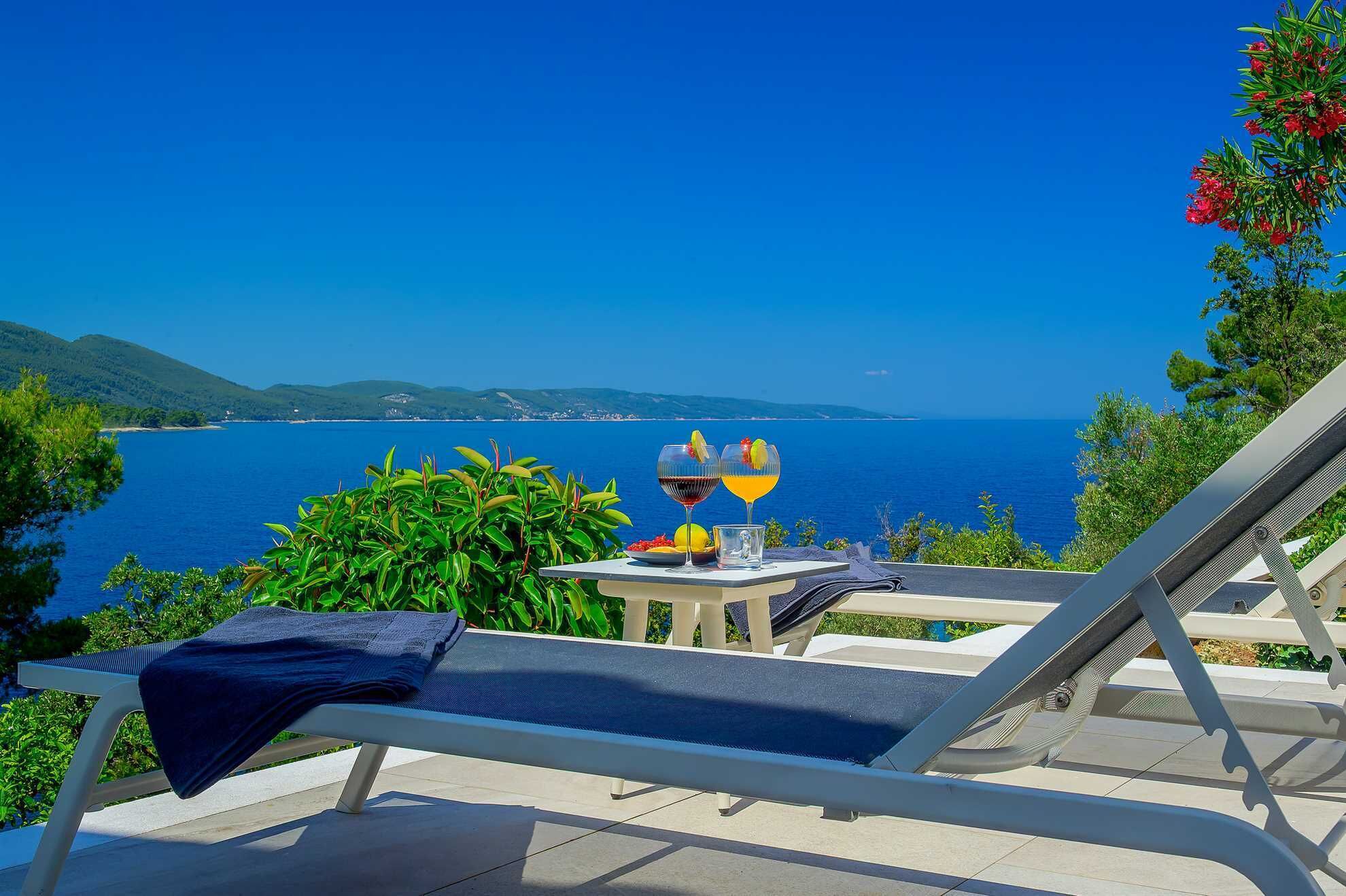 Silla reclinable con una mesa y bebidas, con vista al mar.