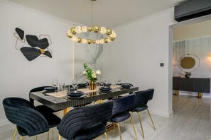 A dining area with a marble wall, a chandelier, and modern chairs. - Beachfront Villa Crystal Bay with Pool (Čara)