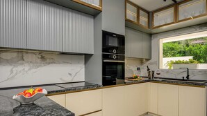 Una cocina moderna con salpicadero de mármol, electrodomésticos integrados y vistas a zonas verdes.