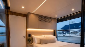 A modern bedroom with a bed, bedside table, and a view of the sea.