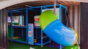 A children's play area with a slide, climbing wall, and a blue play structure.