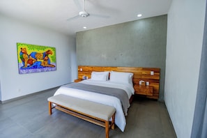 A modern bedroom with a wooden headboard, a single bed, a bench, and a ceiling fan. - Luxury 5-BR villa with private chef, lake views & heated pool (Jal.)