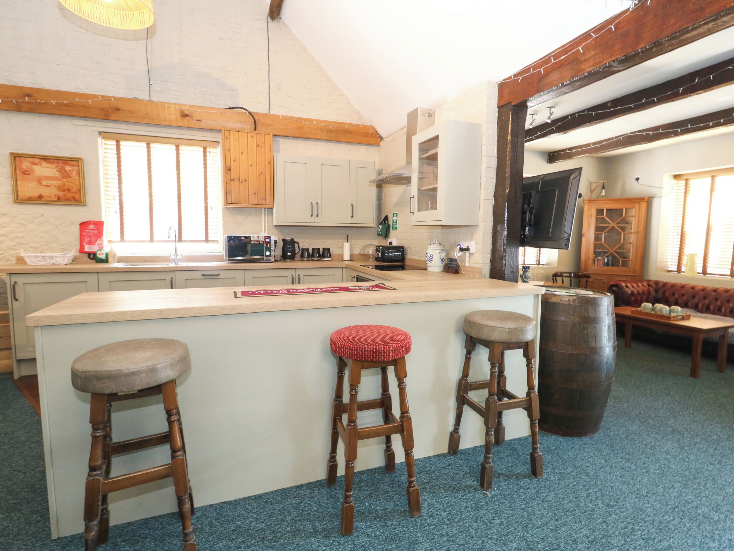 A kitchen with wooden bar stools, a large island, and a dining area with a sofa and table.