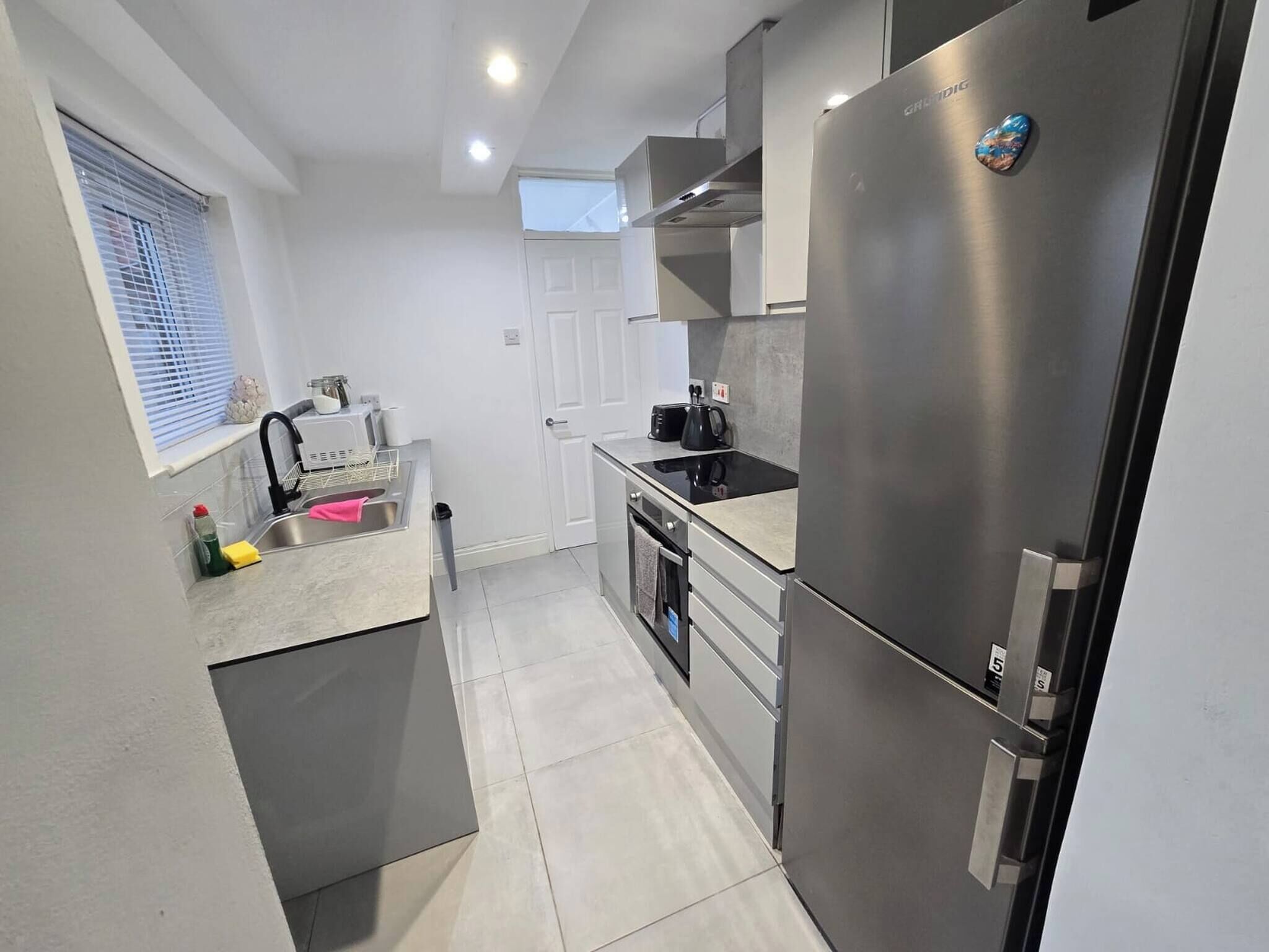 A modern kitchen with stainless steel appliances, a built-in oven, and a window with blinds.