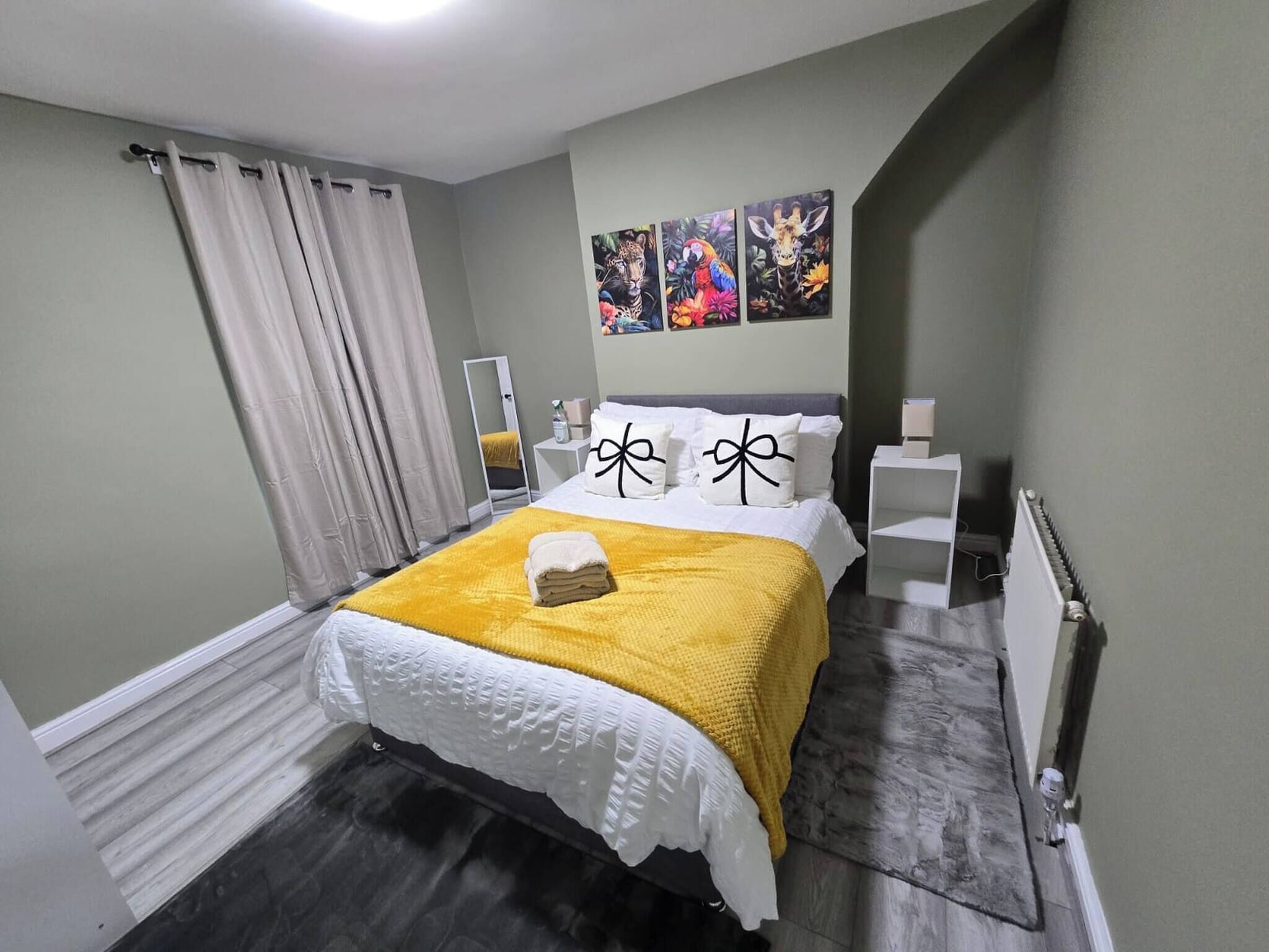 A bedroom with a bed, a mirror, a radiator, and artwork on the wall.