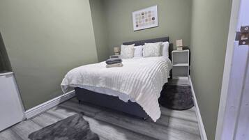 A bedroom with a bed, bedside tables, a rug, and a wall art piece.