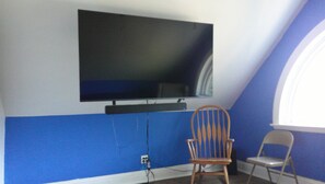 Une pièce avec un téléviseur fixé au mur, un mur bleu et une fenêtre.
