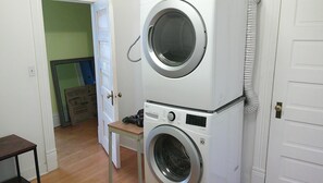 A laundry room with stacked washing machines and a small table.