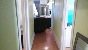 A narrow hallway leading to a kitchen area with a refrigerator and a sink.