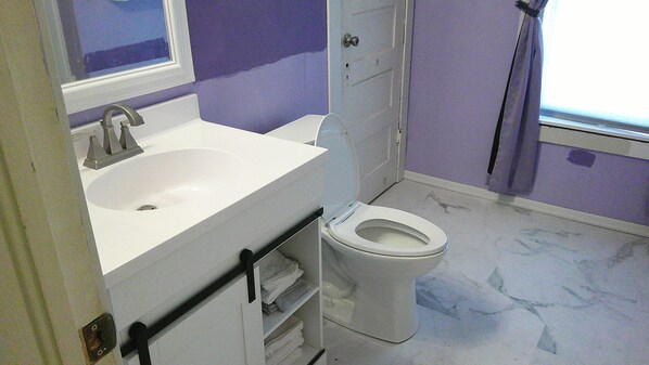 Un baño con lavamanos blanco, inodoro y zona de ducha.