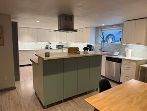 A modern kitchen with a central island, stainless steel appliances, and a window with a view.