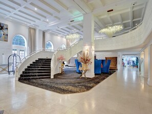 Eine prachtvolle Lobby mit Marmorboden, einer Treppe und einem Chandelier.