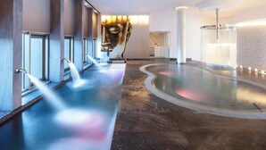 A spa area with a large heated pool, multiple showerheads, and a wall-mounted sculpture. - 4,198ft² Oceanfront Presidential Suite · Jacuzzi Terrace · Butler · Sleeps 8 (B.C.S.)