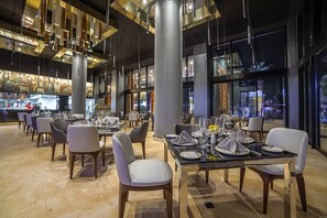 A modern restaurant interior with multiple dining tables, chairs, and a bar area. - 4,198ft² Oceanfront Presidential Suite · Jacuzzi Terrace · Butler · Sleeps 8 (B.C.S.)