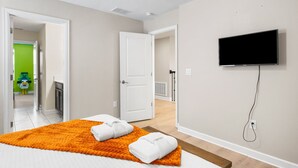 Ein modernes Hotelzimmer mit einem Bett, einem Fernseher und einem durchgegangenen Tür sichtbaren Badezimmer.