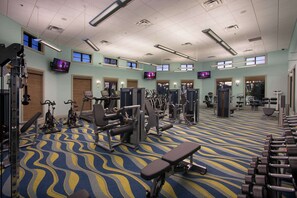 A gym with various exercise equipment, multiple TV screens, and a patterned carpet. - Themed 9BR Villa, Pool, Game Room, Champions Gate (Davenport)