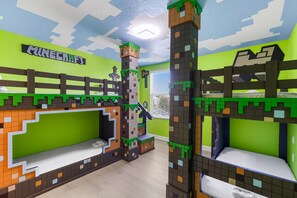 Habitació infantil amb tema de Minecraft, amb llits superposats, una estructura de castell i un cartell de 'Minecraft' a la paret.