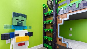 Ein Zimmer mit grüner Wand, einem Bett mit weißer Matratze und einem an der Wand befestigten Regal mit grün-schwarzem Dekor.