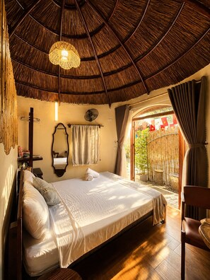 A room with a bed, a fan, a mirror, and a view of the outside. - Sora Tam Coc (Nam Hoa Lu)