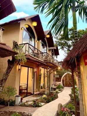 A traditional-style building with a balcony, a thatched roof, and a pathway leading to a door. - Sora Tam Coc  (Nam Hoa Lu)