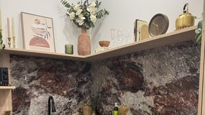 Eine Küche mit Marmorfliesenspiegel, Holzschränken, einer Kaffeemaschine und verschiedenen Küchenutensilien auf der Arbeitsplatte.