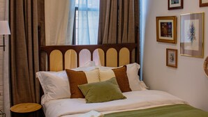 Ein ordentlich gemachtes Bett mit einer grünen Tagesdecke, einem Holz-Kopfteil und einem Paar Handtücher mit einem Logo.