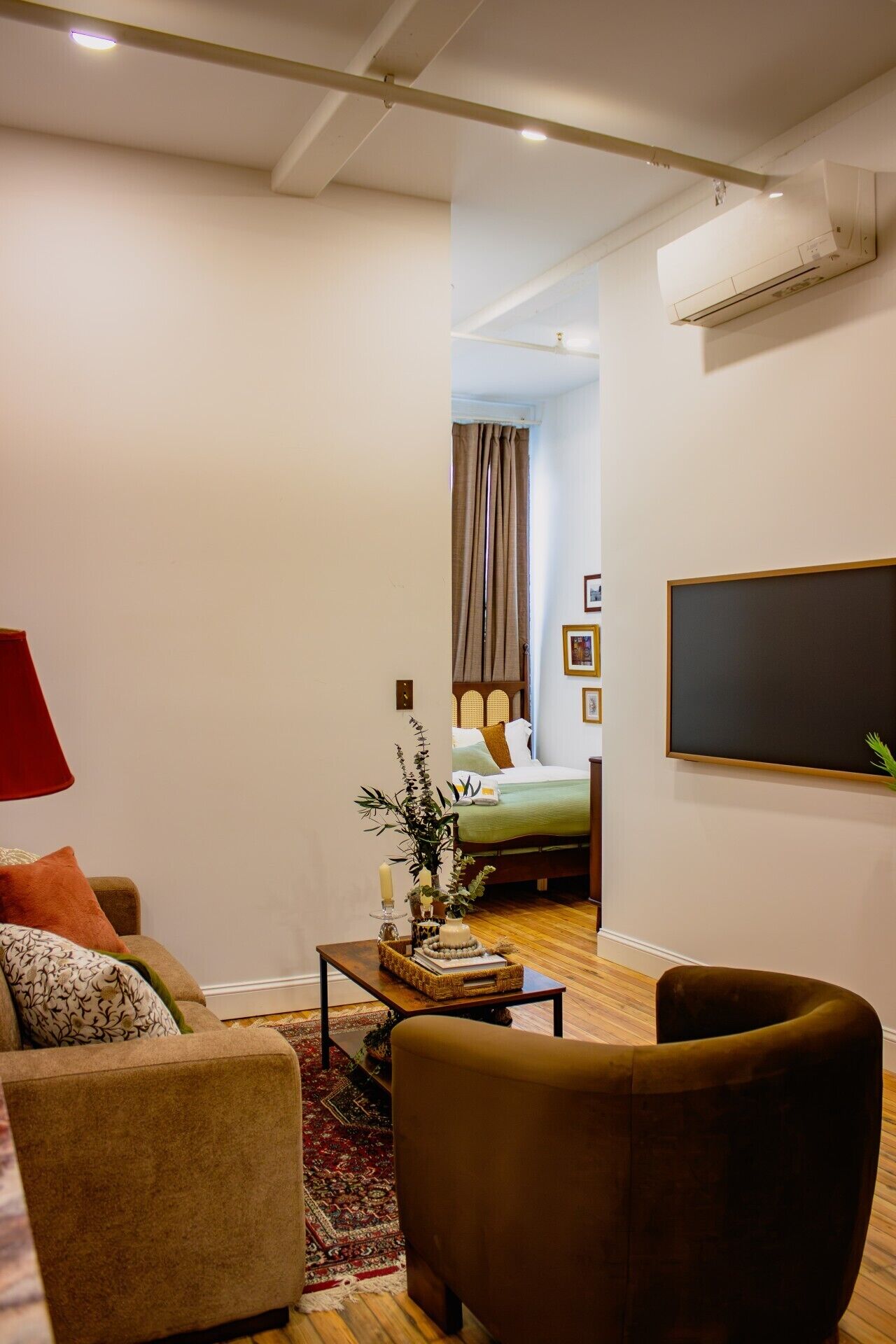 Uma sala de estar com um sofá, uma mesa de centro e uma televisão fixada na parede.