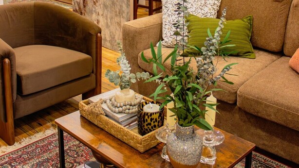 Ein Wohnzimmer mit Sofa, Sessel, Couchtisch und einer Küchenzeile mit Holzausbau und Marmorarbeitsplatte.