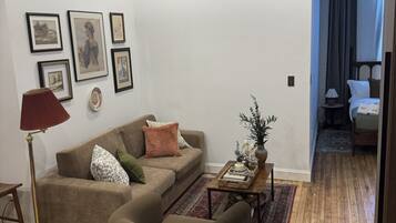 A living room with a sofa, a coffee table, a floor lamp, and framed artwork on the wall.