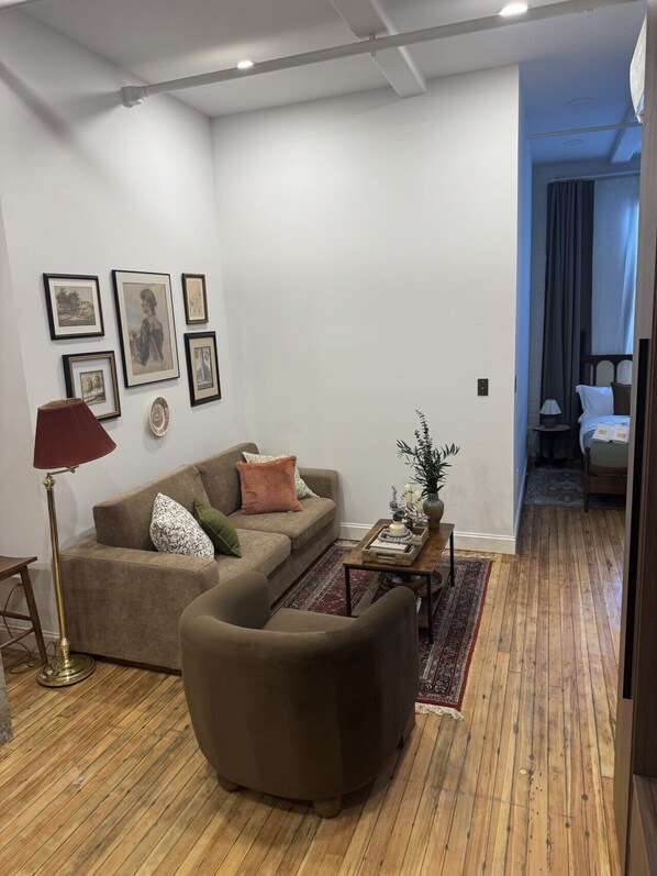 A living room with a sofa, a coffee table, a floor lamp, and framed artwork on the wall.