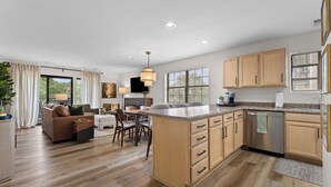 Une cuisine moderne avec des meubles en bois, un îlot central et un coin repas comprenant un canapé et des chaises.