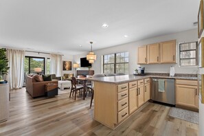 A modern kitchen with wooden cabinets, a central island, and a dining area with a sofa and chairs. - Sagewood: Two Kings, Fireplace and Pool (Branson)