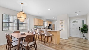 Une cuisine moderne avec des meubles en bois, un îlot central et un coin repas doté de chaises en bois.