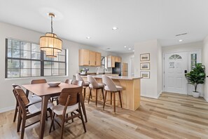 A modern kitchen with wooden cabinets, a central island, and a dining area with wooden chairs. - Sagewood: Two Kings, Fireplace and Pool (Branson)