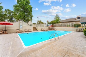 A swimming pool with lounge chairs and umbrellas, surrounded by a fence and trees. - Sagewood: Two Kings, Fireplace and Pool (Branson)