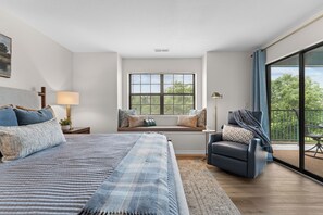 A bedroom with a large bed, a window seat, a chair, and a balcony. - Sagewood: Two Kings, Fireplace and Pool (Branson)